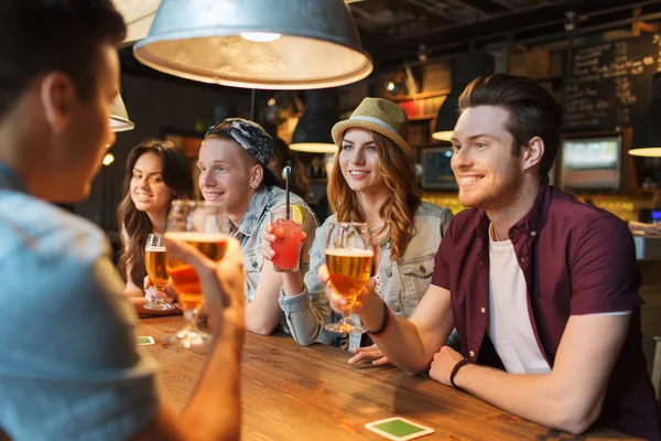 Amigos felizes com bebidas conversando no bar ou pub — Fotografia de Stock