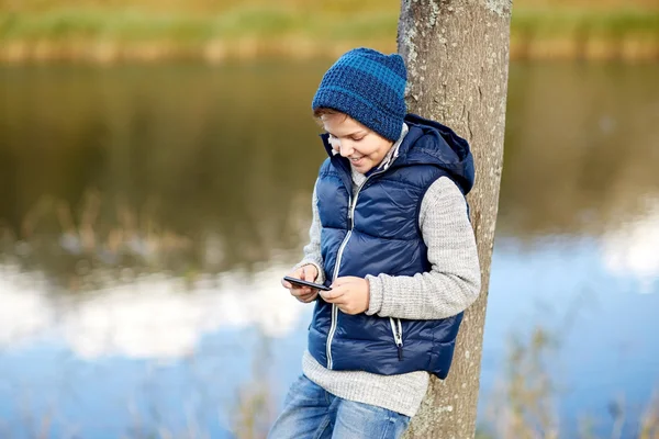 Szczęśliwy chłopiec gra na smartphone na zewnątrz Obrazy Stockowe bez tantiem