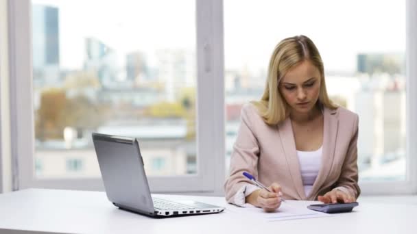 Mujer de negocios con portátil, calculadora y papeles — Vídeos de Stock