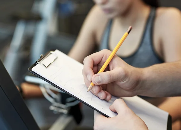 Primer plano de las manos del entrenador con portapapeles en el gimnasio — Foto de Stock