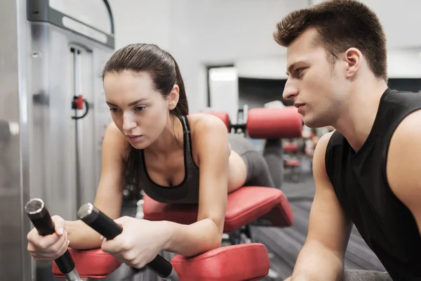 Mujer joven con entrenador haciendo ejercicio en la máquina de gimnasio — Foto de Stock