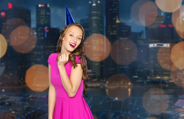 Happy young woman in party cap over night city — Stockfoto