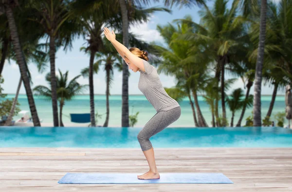 Mujer haciendo yoga en silla pose sobre estera — Foto de Stock