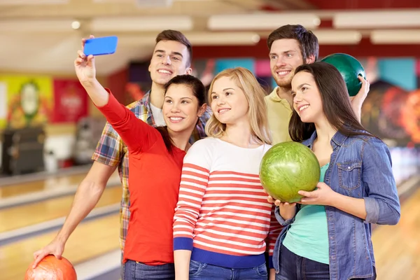 Glada vänner med smartphone i bowling club — Stockfoto