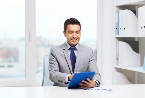 Улыбающийся бизнесмен с планшетным ПК в офисе — стоковое фото