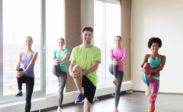 Gruppe lächelnder Menschen, die im Fitnessstudio trainieren — Stockfoto