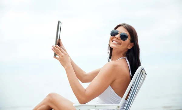 Lachende vrouw met tablet pc om te zonnebaden op het strand — Stockfoto