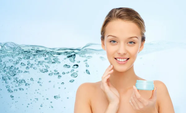 Happy young woman applying cream to her face — Stock Photo, Image