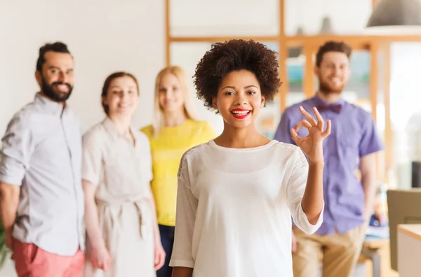 Lycklig kvinna visar ok över kreativa office team — Stockfoto