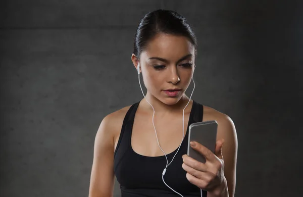 Kvinna med smartphone och hörlurar i gym — Stockfoto