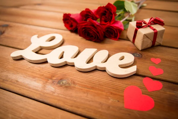 Primer plano de regalo, palabra amor, rosas rojas y corazones — Foto de Stock