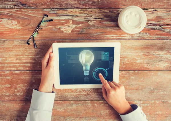 Close up of hands with tablet pc and lighting bulb — Stock Photo, Image