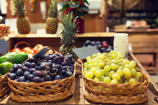 Виноград в корзинах с табличками на продовольственном рынке — стоковое фото