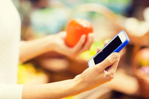 Woman with smartphone and persimmon in market — Stock Photo, Image