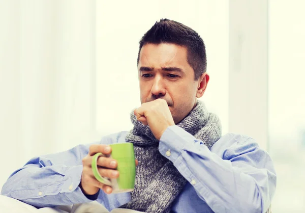 Sjuk man med influensa dricka te och hosta hemma — Stockfoto