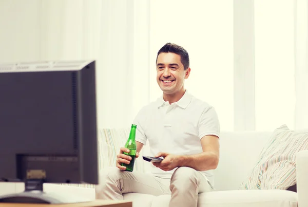 Sorrindo homem assistindo tv e bebendo cerveja em casa — Fotografia de Stock