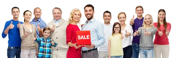 Happy people with red sale sign showing thumbs up — Stock Photo, Image