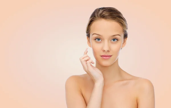 Jonge vrouw aanbrengen crème op haar gezicht — Stockfoto