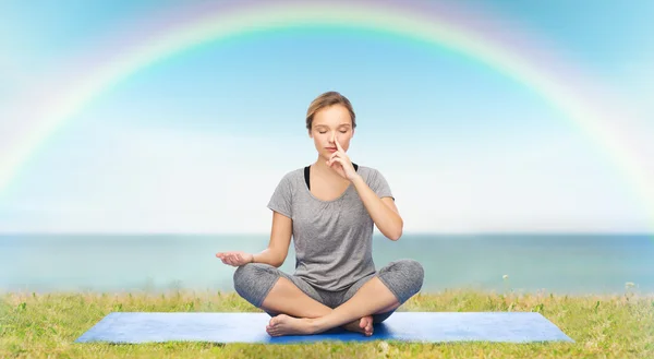 Mujer haciendo meditación de yoga en pose de loto en la estera —  Fotos de Stock