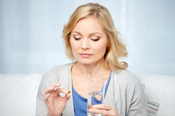 Kvinna med medicin och vatten glas hemma — Stockfoto