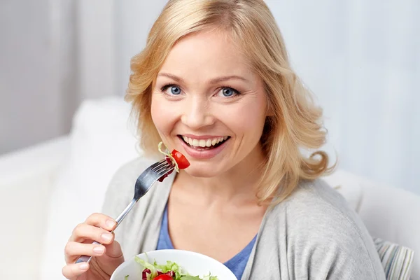 Lächelnde Frau mittleren Alters, die zu Hause Salat isst — Stockfoto