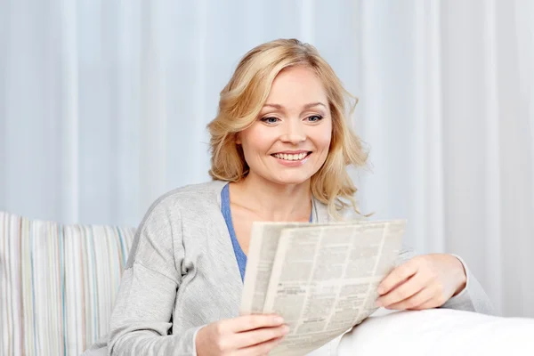 Mulher sorridente lendo jornal em casa — Fotografia de Stock