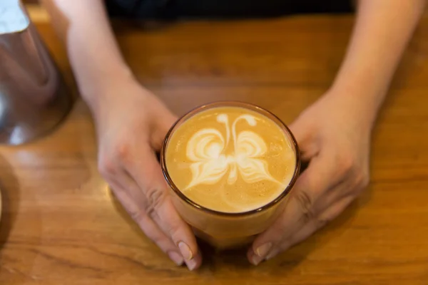 Close up van handen met latte kunst in koffiekopje — Stockfoto