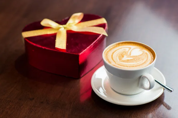 Close up of gift box and coffee cup on table — Stock Photo, Image