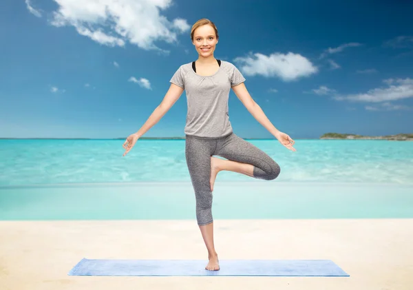 Mujer haciendo yoga en pose de árbol en la estera — Foto de Stock