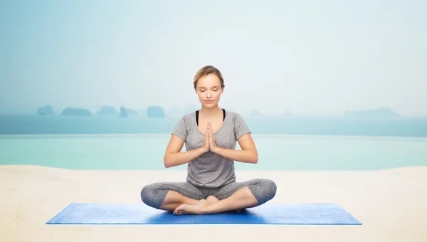 Mujer haciendo meditación de yoga en pose de loto en la estera —  Fotos de Stock