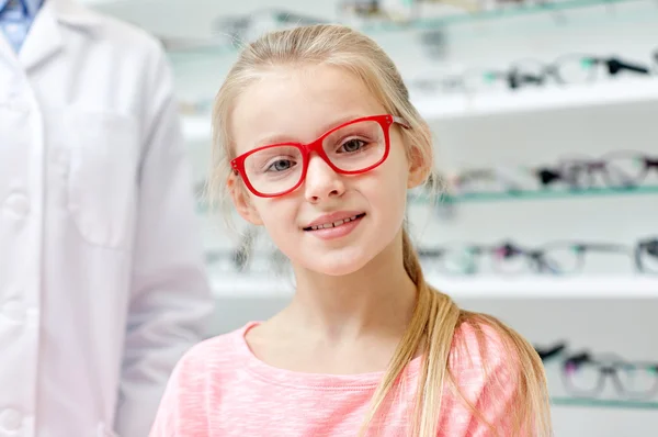 Menina em óculos com óptico na loja de óptica — Fotografia de Stock