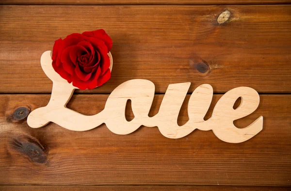 Zbliżenie słowo miłość wyłącznik z czerwoną różą na drewno — Zdjęcie stockowe