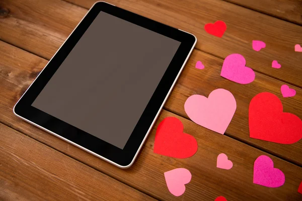 Close up of tablet pc and hearts on wood — Stock Photo, Image