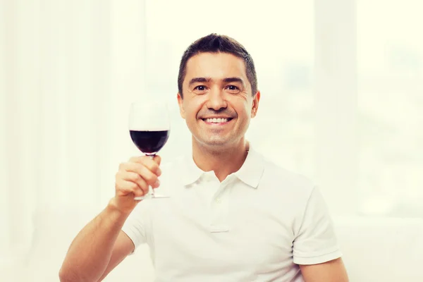 Homem feliz bebendo vinho tinto de vidro em casa — Fotografia de Stock