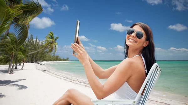 Mulher sorridente com tablet pc banhos de sol na praia — Fotografia de Stock