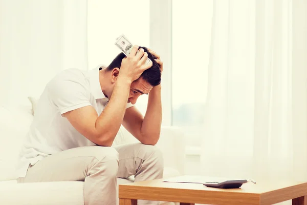 Hombre con dinero y calculadora en casa —  Fotos de Stock