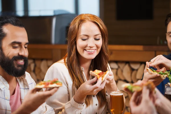 Friends eating pizza with beer at restaurant — Stock Photo, Image