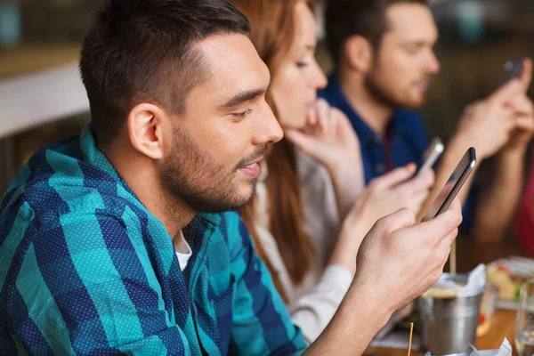 Amigos com smartphones jantando no restaurante — Fotografia de Stock