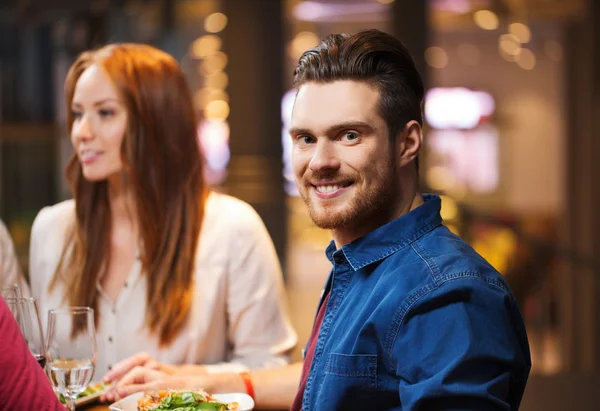 Счастливый мужчина с друзьями, ужинающими в ресторане — стоковое фото