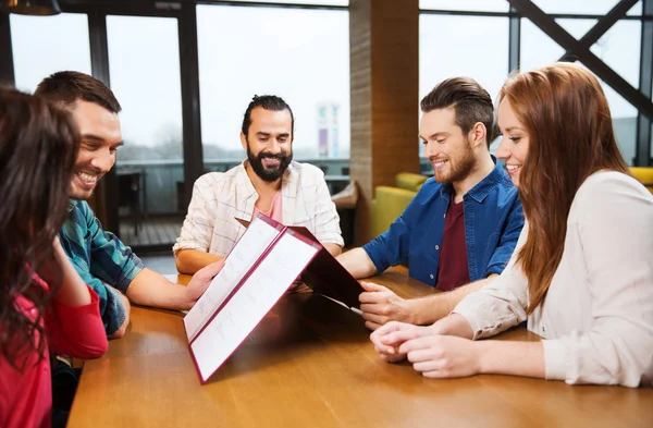 Smiling friends discussing menu at restaurant — Stock Photo, Image