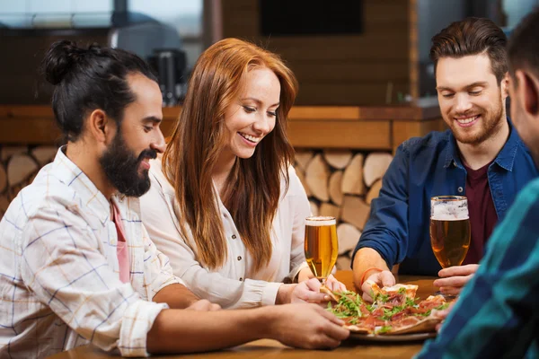 Amigos que compartilham pizza com cerveja na pizzaria — Fotografia de Stock