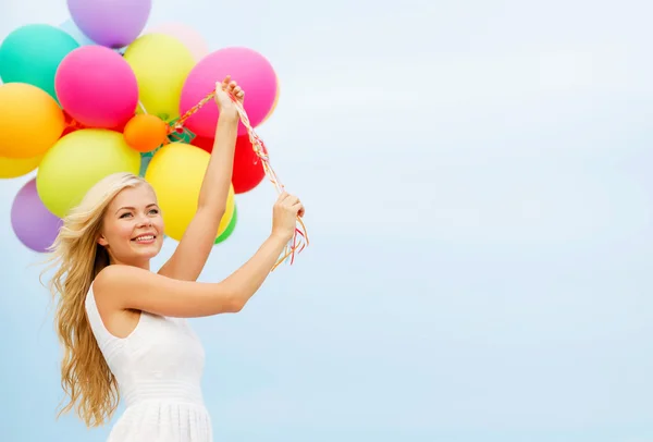 Leende kvinna med färgglada ballonger utanför — Stockfoto