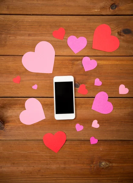 Close up of smartphone and hearts on wood — Stock Photo, Image