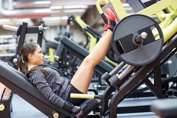 Mujer flexionar los músculos en la máquina de prensa de piernas en el gimnasio — Foto de Stock