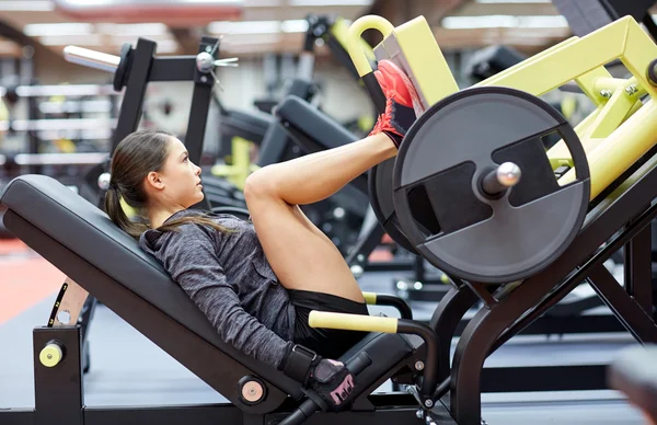 Kobieta napina mięśnie na maszynie do prasowania nóg w siłowni — Zdjęcie stockowe