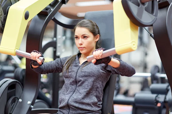 Woman flexing muscles on chest press gym machine — Stock Photo, Image