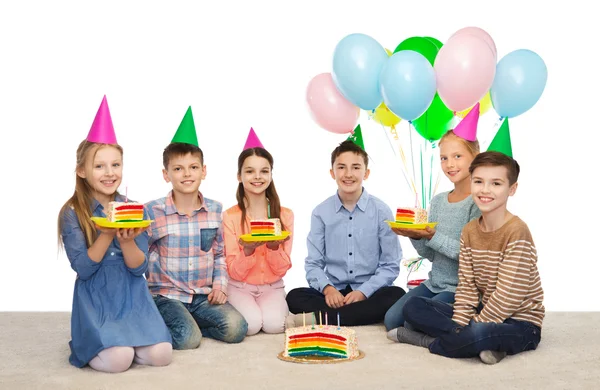 Glada barn i partyhattar med födelsedagstårta — Stockfoto