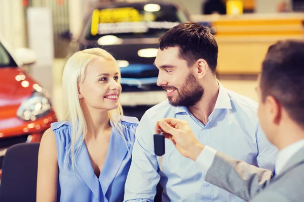 Casal feliz com revendedor de carro em auto show ou salão — Fotografia de Stock