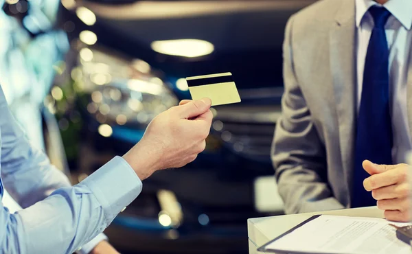 Customer giving credit card to car dealer in salon — Stock Photo, Image