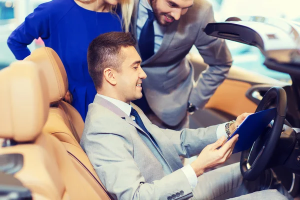 Feliz pareja con concesionario de coches en auto show o salón — Foto de Stock